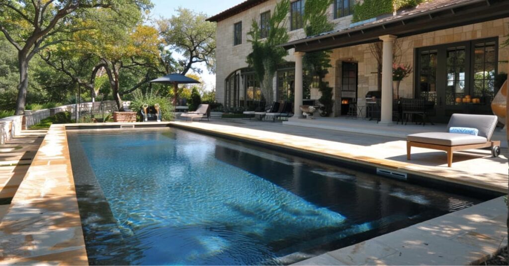 gunite pool behind house with outdoor kitchen seating and patio cover