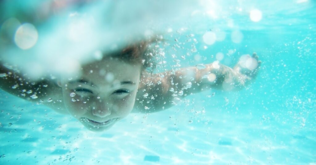 child swimming under water in pool